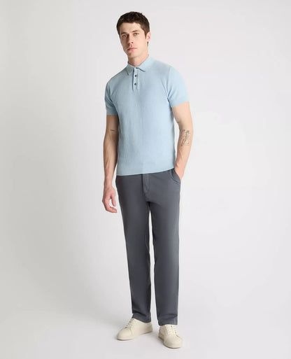 Man wearing a light blue polo shirt and gray pants on a white background