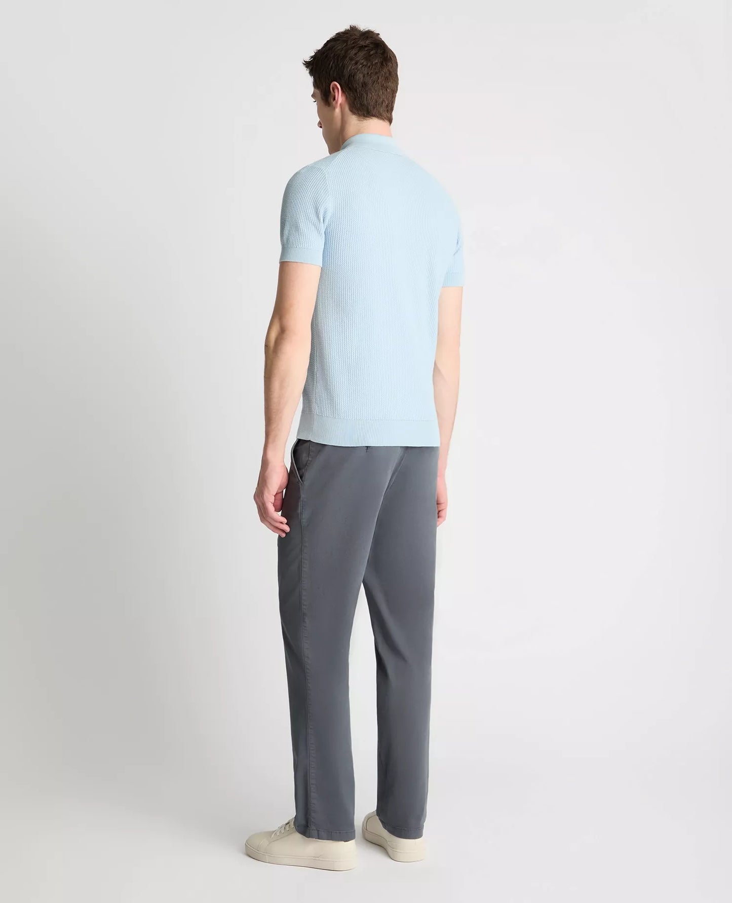 Person wearing a light blue shirt and gray pants on a white background