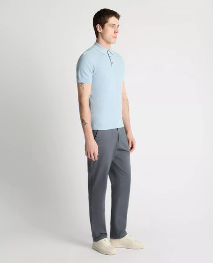 Man wearing a light blue polo shirt and gray pants on a white background
