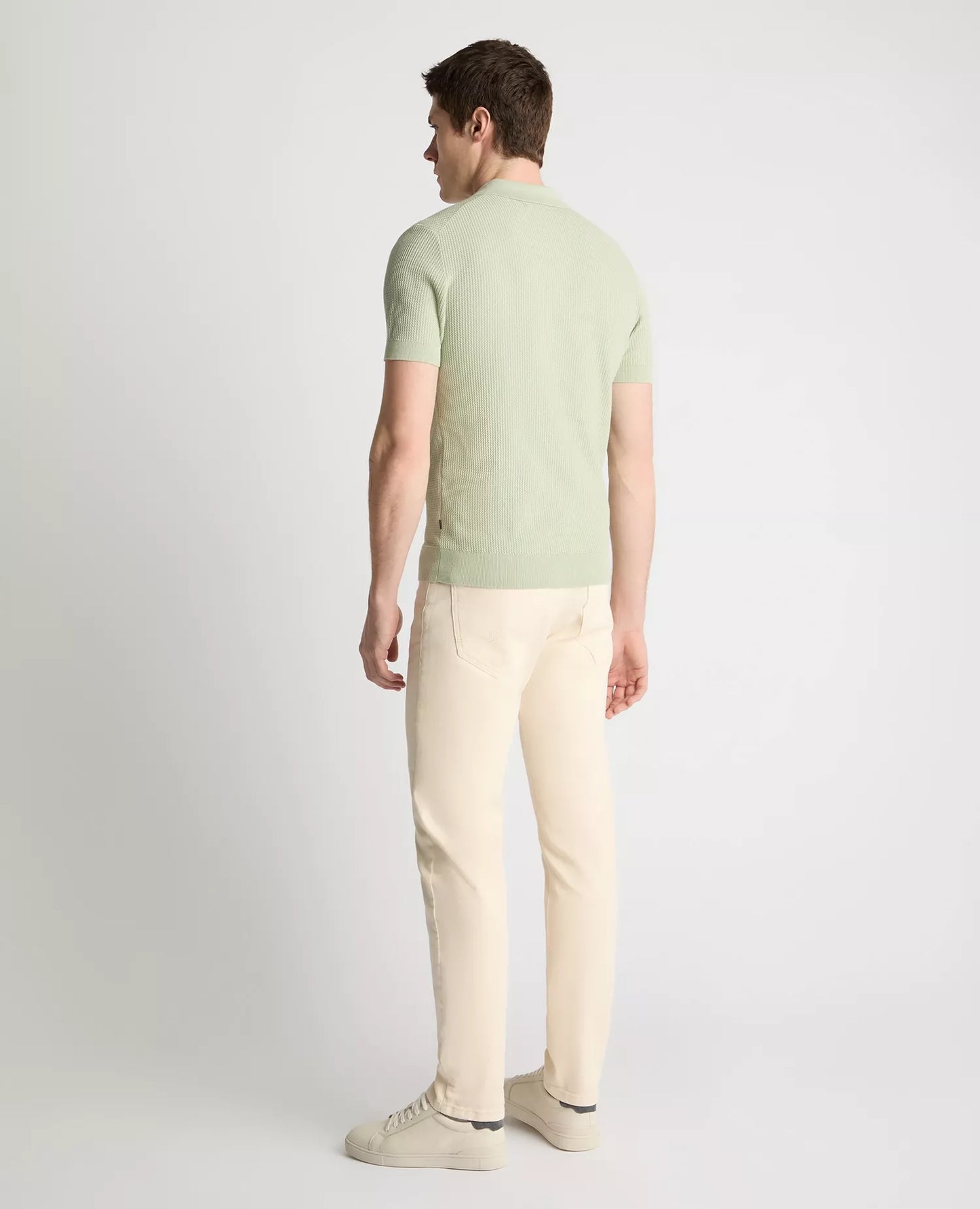 Man wearing a light green t-shirt and beige pants on a white background