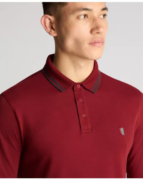 Man wearing a red polo shirt with a small logo on a gray background