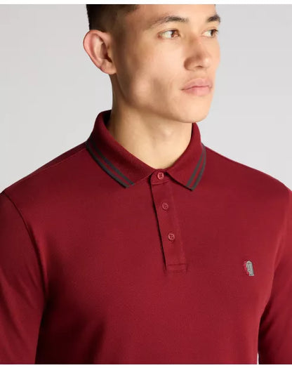 Man wearing a red polo shirt with a small logo on a gray background