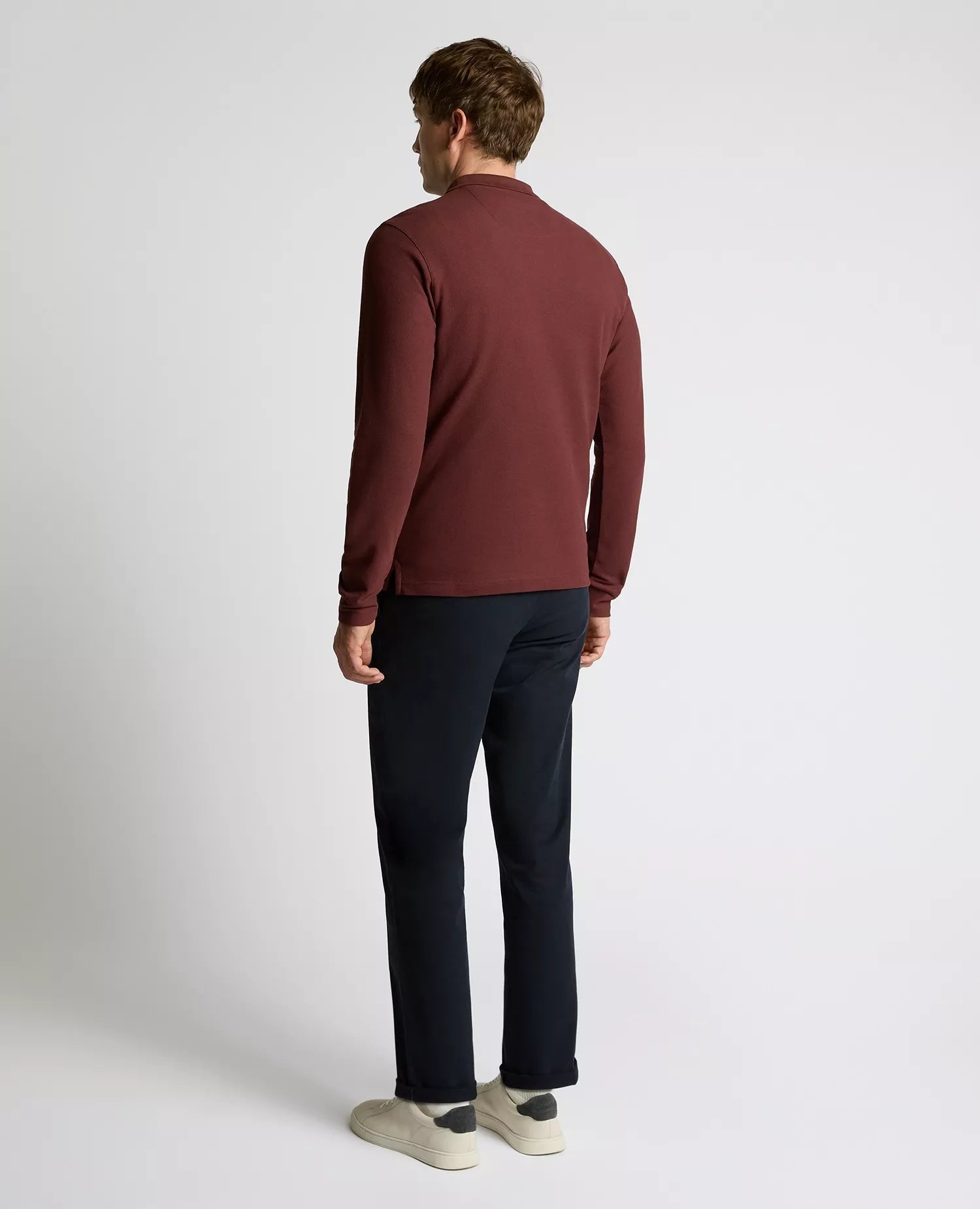 Man wearing a maroon sweater and black pants on a white background