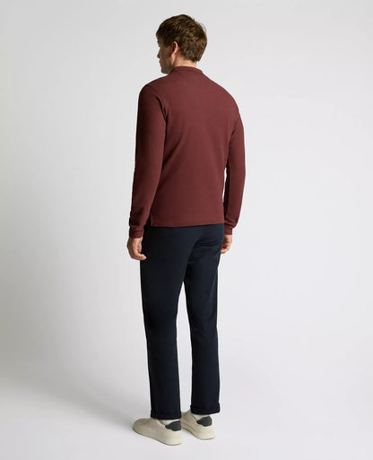 Man wearing a maroon sweater and black pants on a white background
