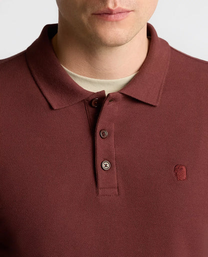 Close-up of a maroon polo shirt with a brand logo on a white background