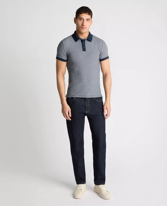 Man wearing a patterned polo shirt and dark jeans on a white background