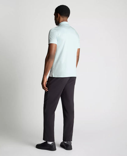 Man wearing a light blue polo shirt and black pants on a white background