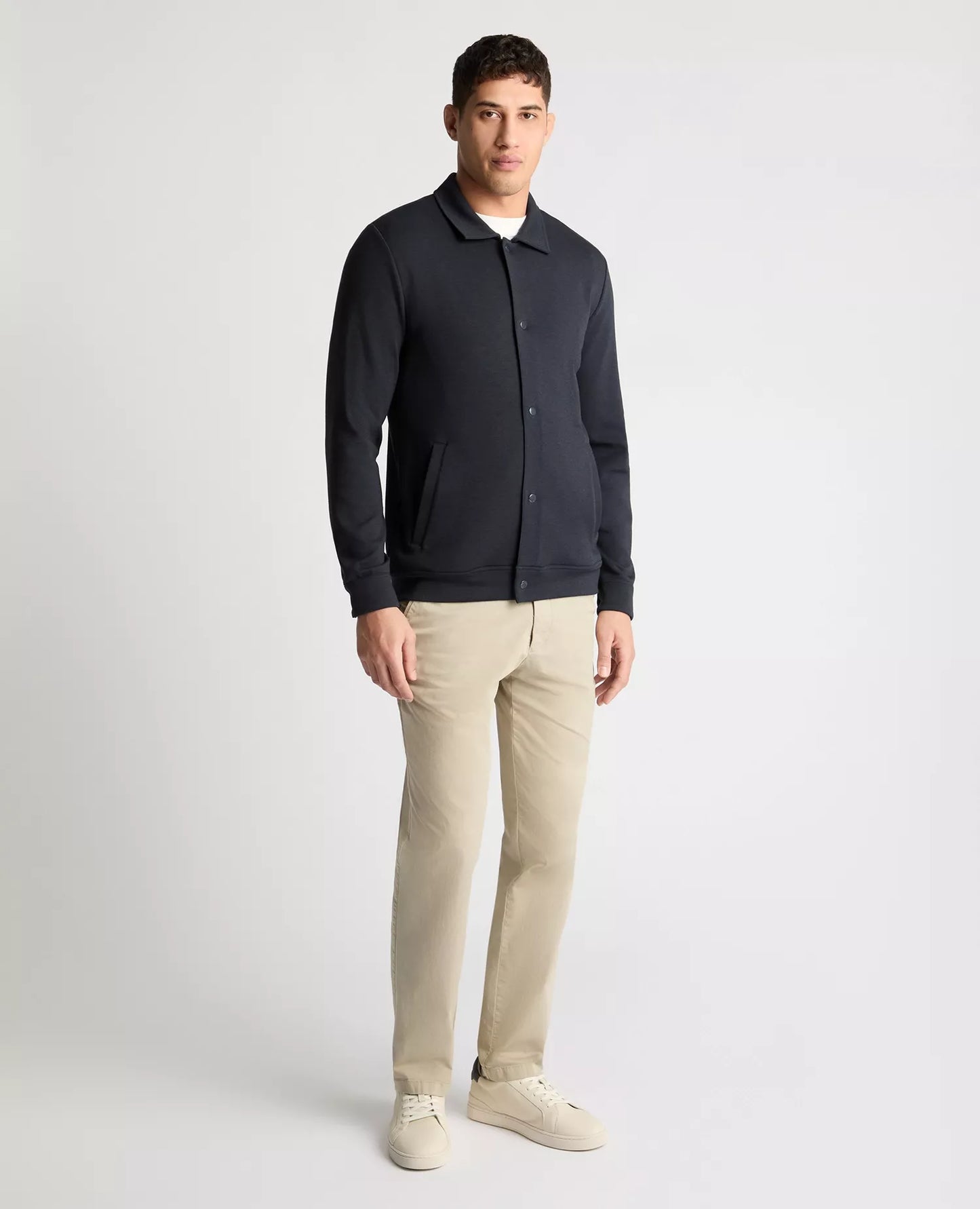Man wearing a dark blue shirt and beige pants on a white background