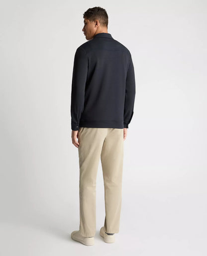Man wearing a dark jacket and beige pants on a white background