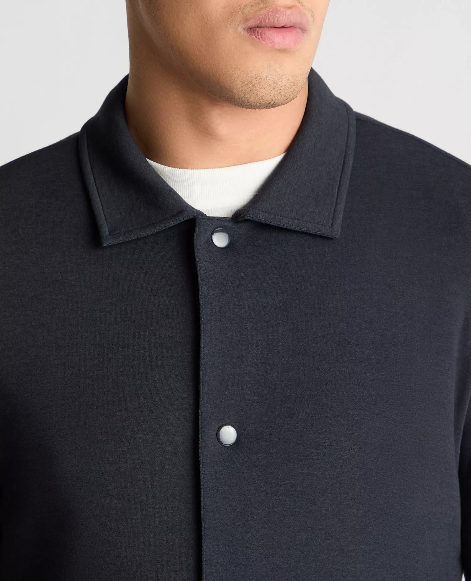 Close-up of a dark gray button-up shirt with a white collar on a neutral background
