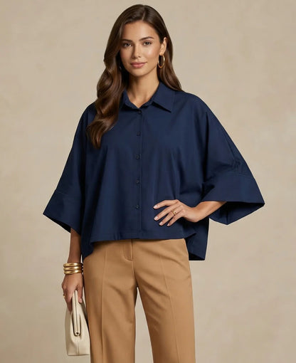 Woman wearing a navy blue blouse and tan pants against a beige background