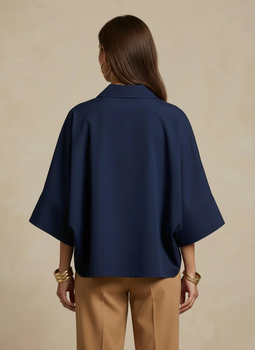 Person wearing a navy blue shirt and beige pants against a beige background