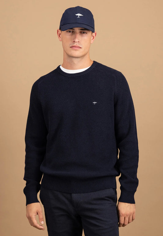 Man wearing a navy sweater and cap on a beige background