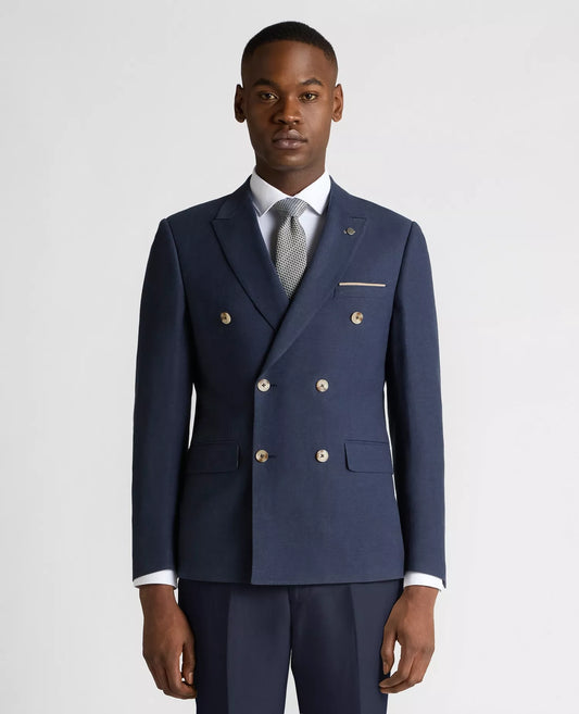 Man wearing a navy blue suit with gold buttons on a light gray background