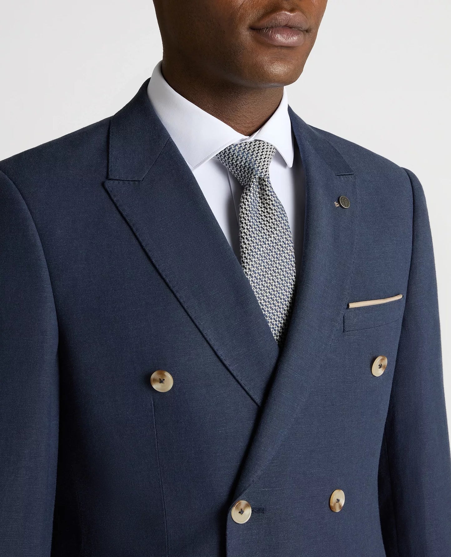 Navy blue suit jacket with white shirt and patterned tie on a neutral background