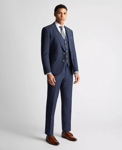 Man wearing a blue suit with brown shoes on a light gray background