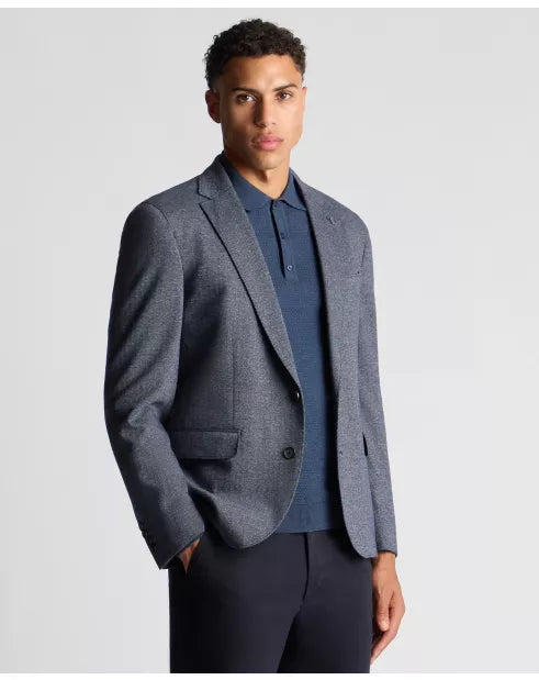 Man wearing a gray blazer over a blue shirt on a light gray background