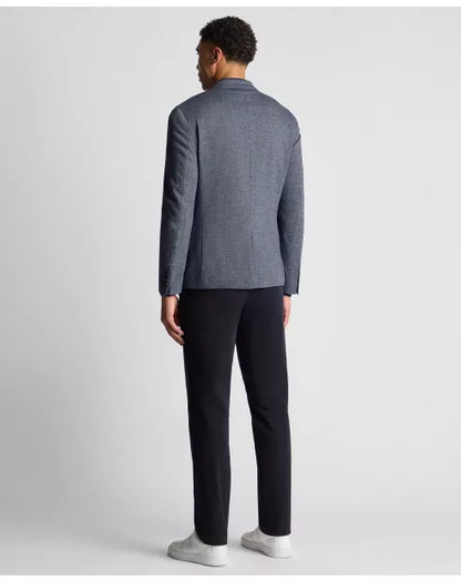 Man wearing a gray blazer and black pants on a light gray background