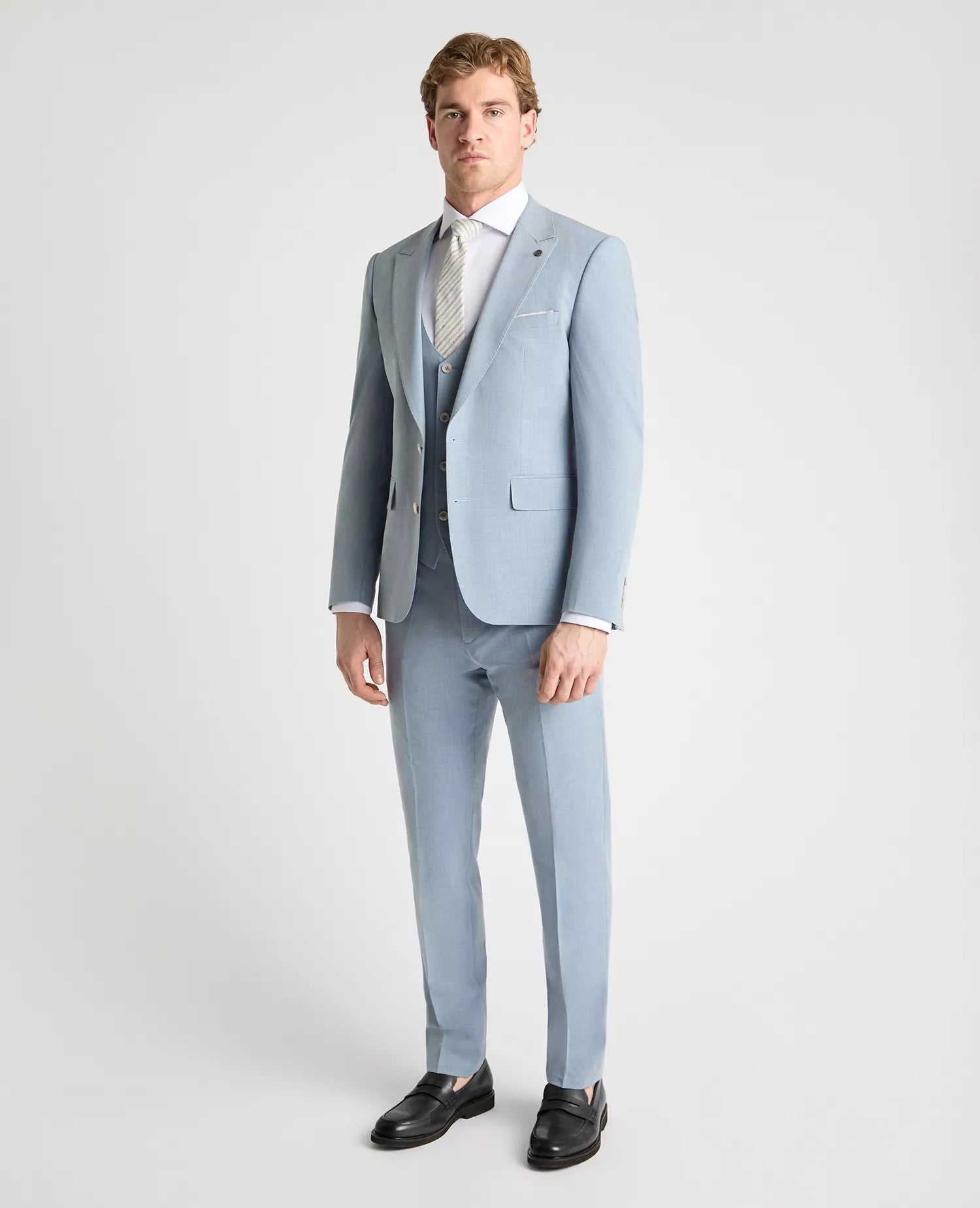 Man wearing a light blue suit with a white shirt and tie on a white background