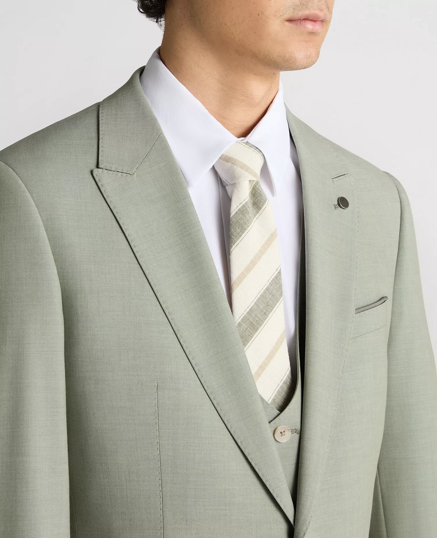 Man wearing a light gray suit with a striped tie on a plain background