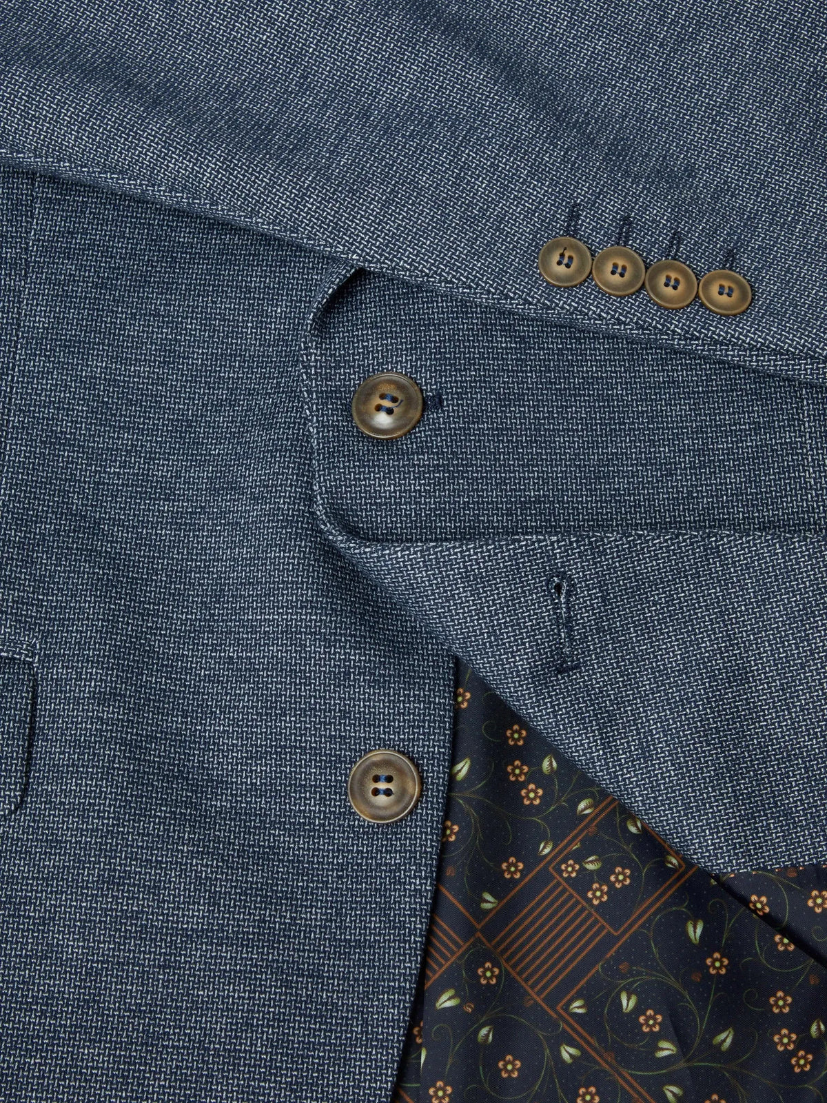 Close-up of a blue textured fabric with buttons and a patterned lining.