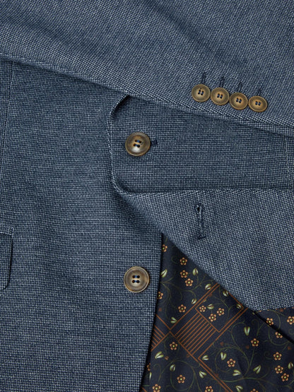 Close-up of a blue textured fabric with buttons and a patterned lining.