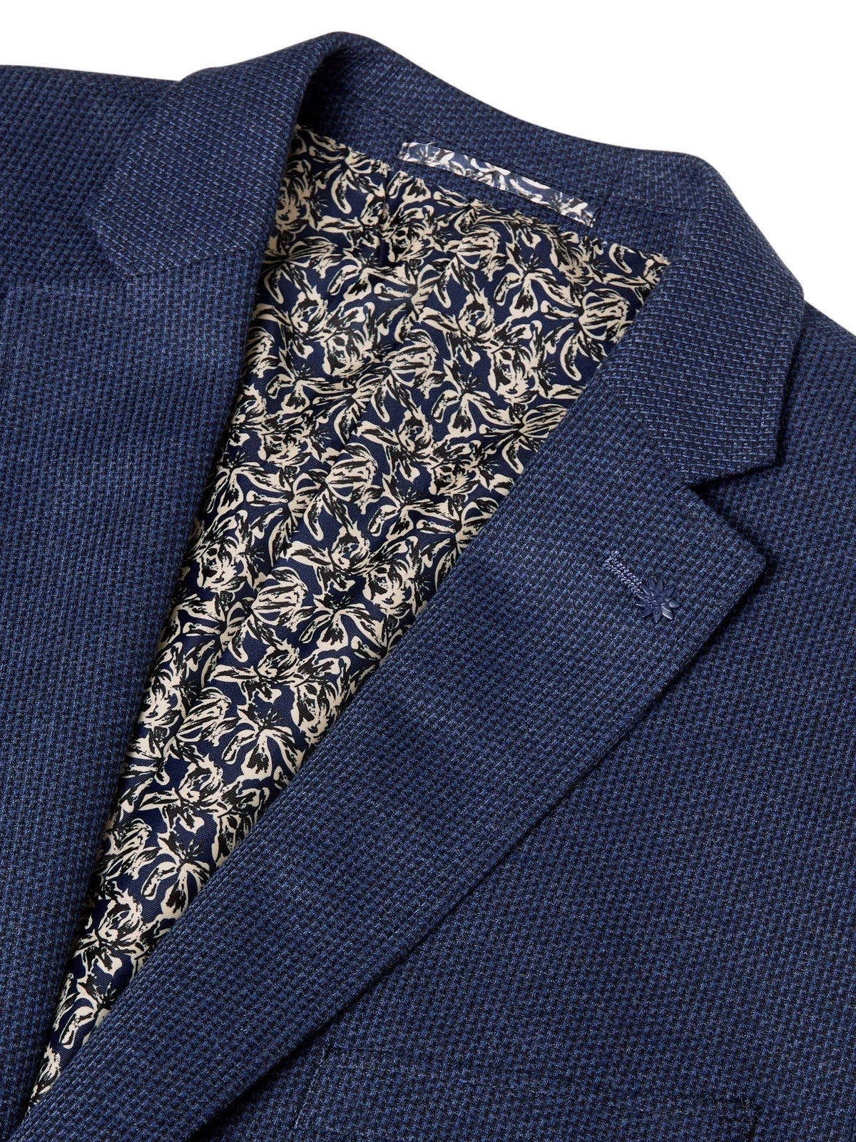 Close-up of a navy blue textured blazer jacket with a patterned lining in navy, beige, and white.