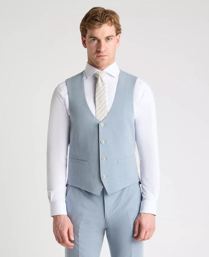 Man wearing a light blue suit vest and pants with a white shirt and tie on a plain background