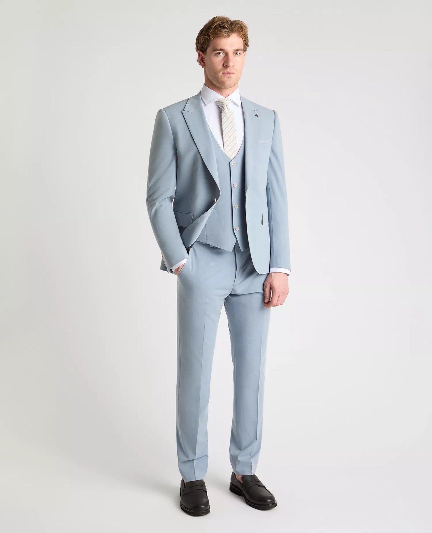 Man wearing a light blue suit with a white shirt on a plain background