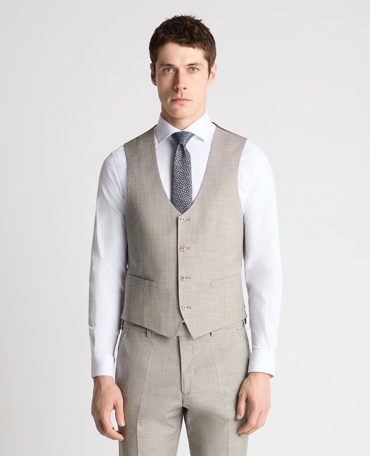 Man wearing a gray checkered vest over a white shirt with a patterned tie on a light gray background