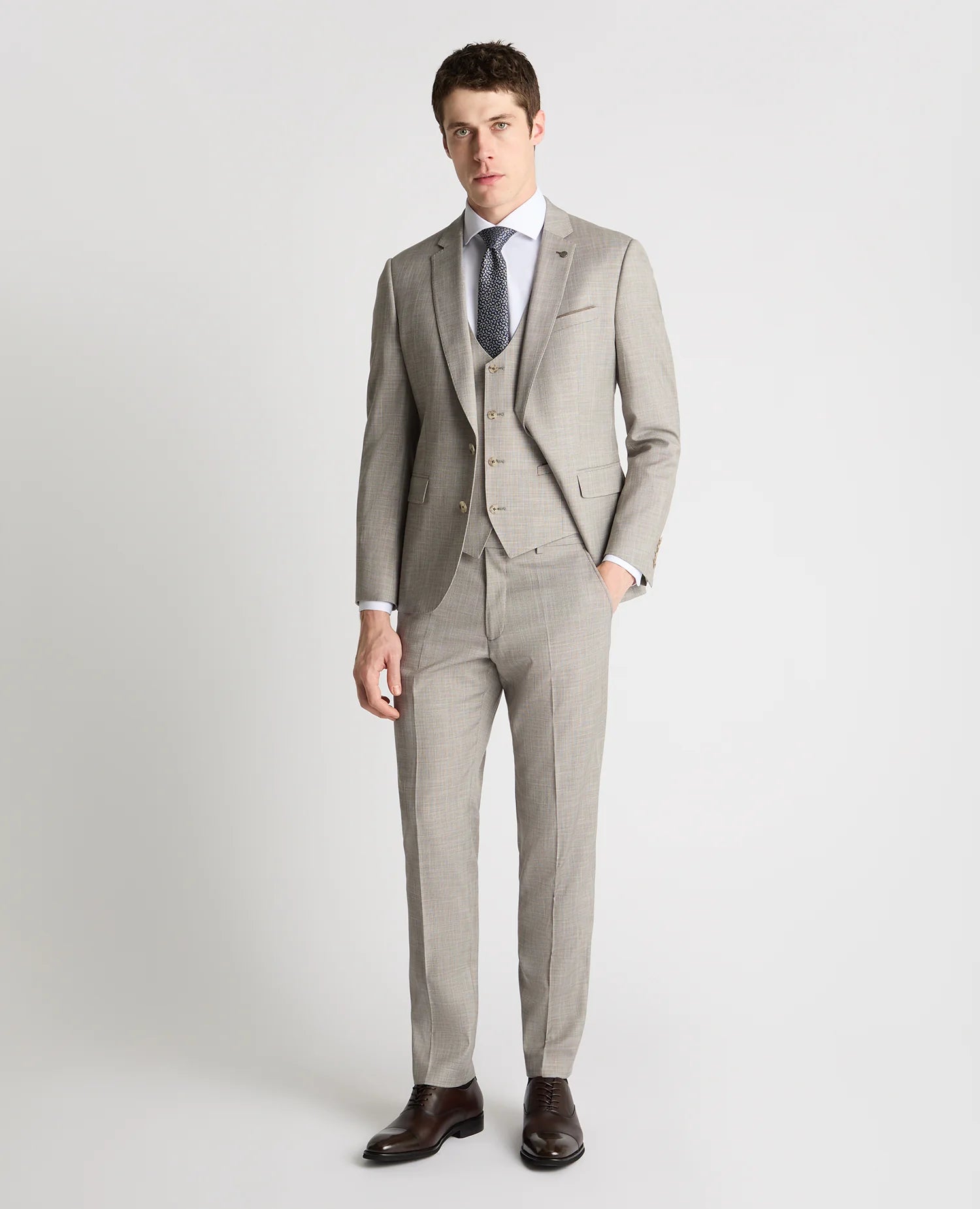 Man wearing a light gray suit with a white shirt and dark tie on a white background