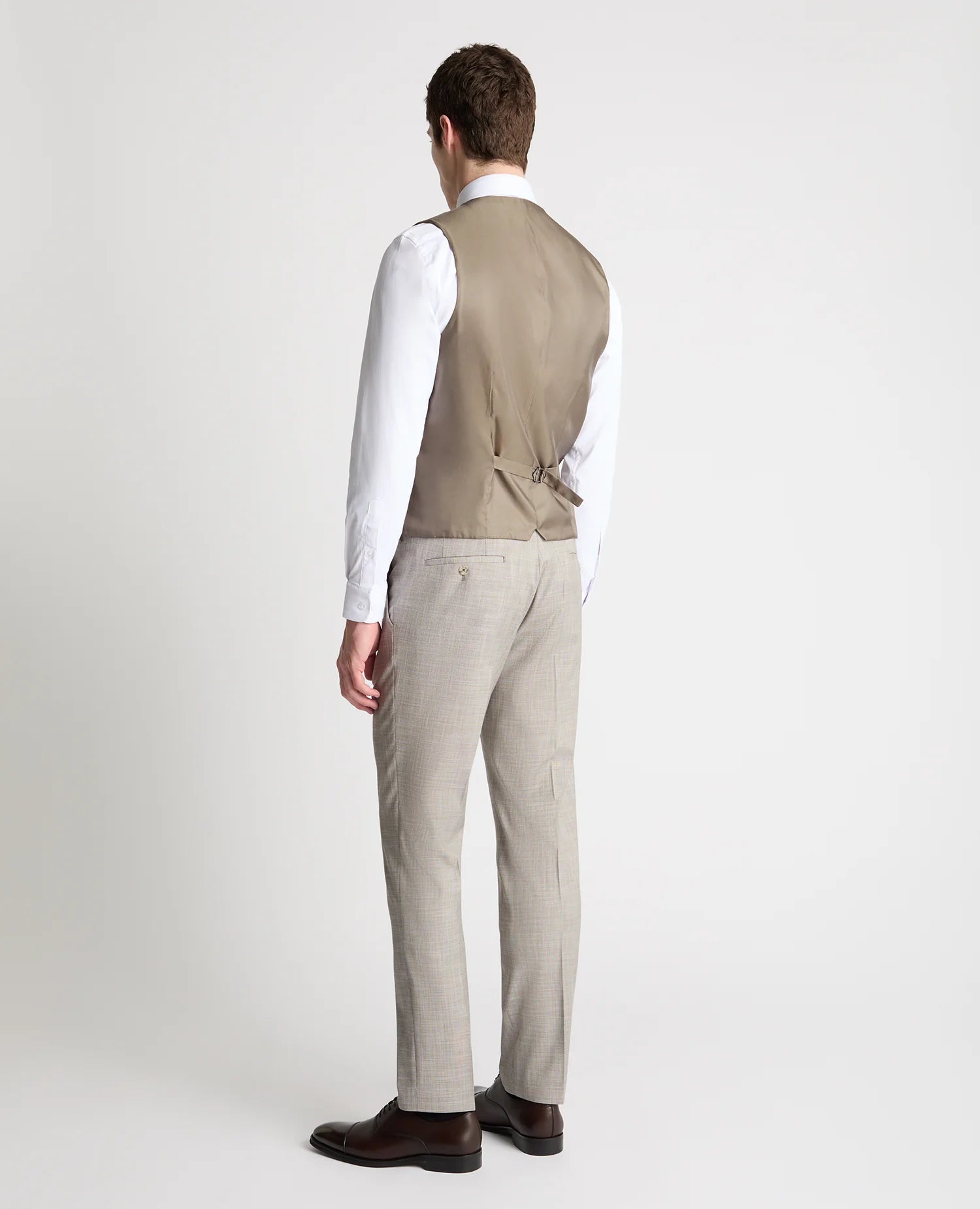 Man wearing a beige vest and pants on a white background