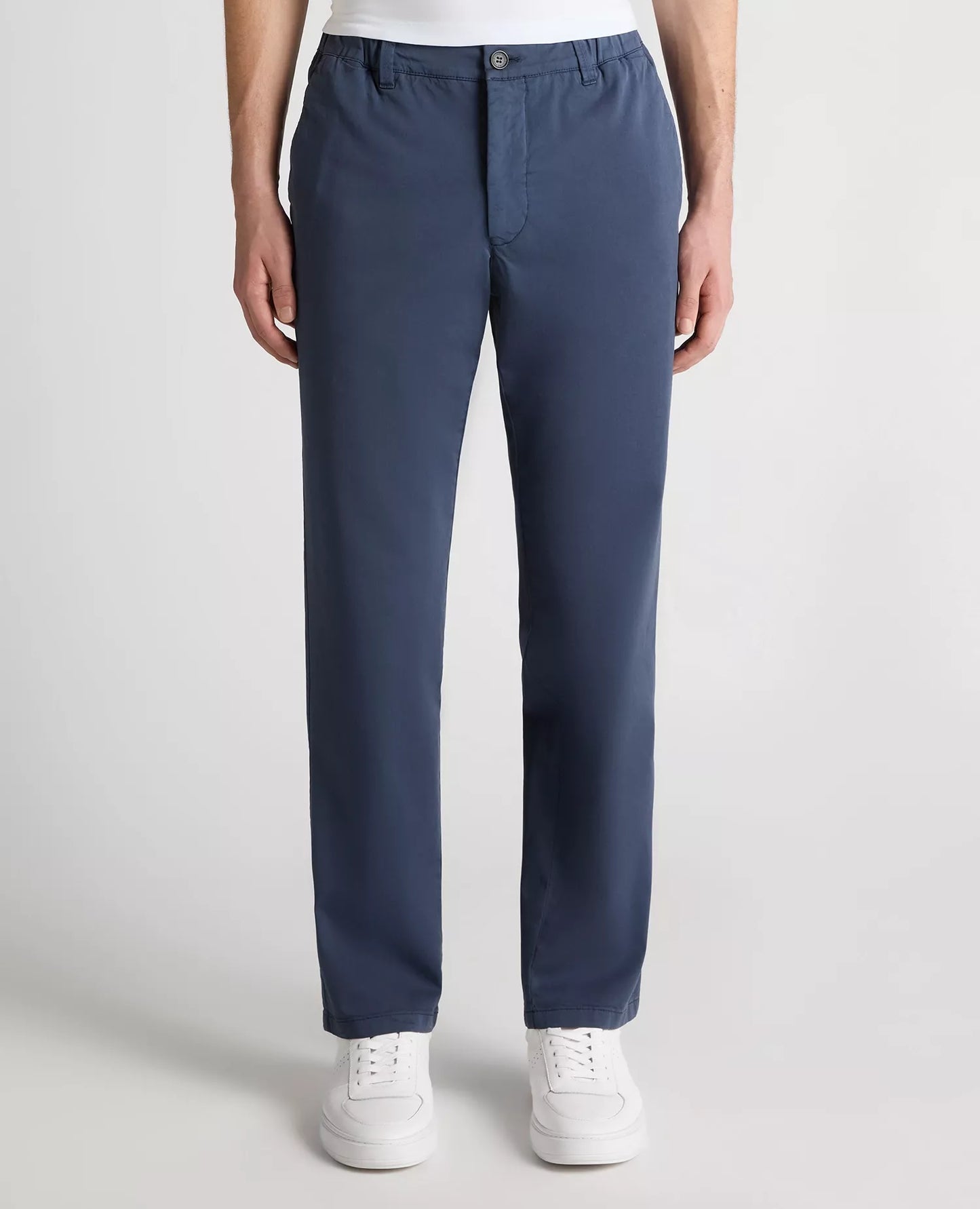 Person wearing blue pants and white sneakers on a light gray background