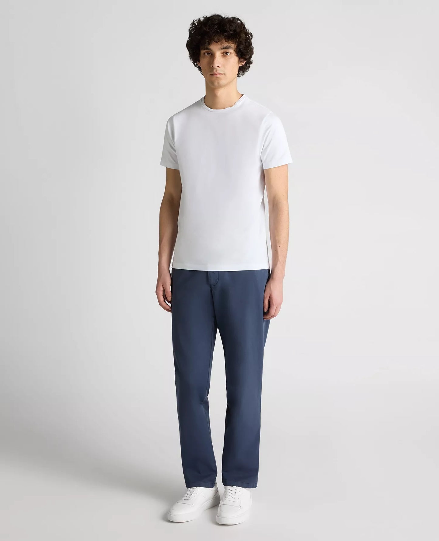 Person wearing a white t-shirt and blue pants on a plain background