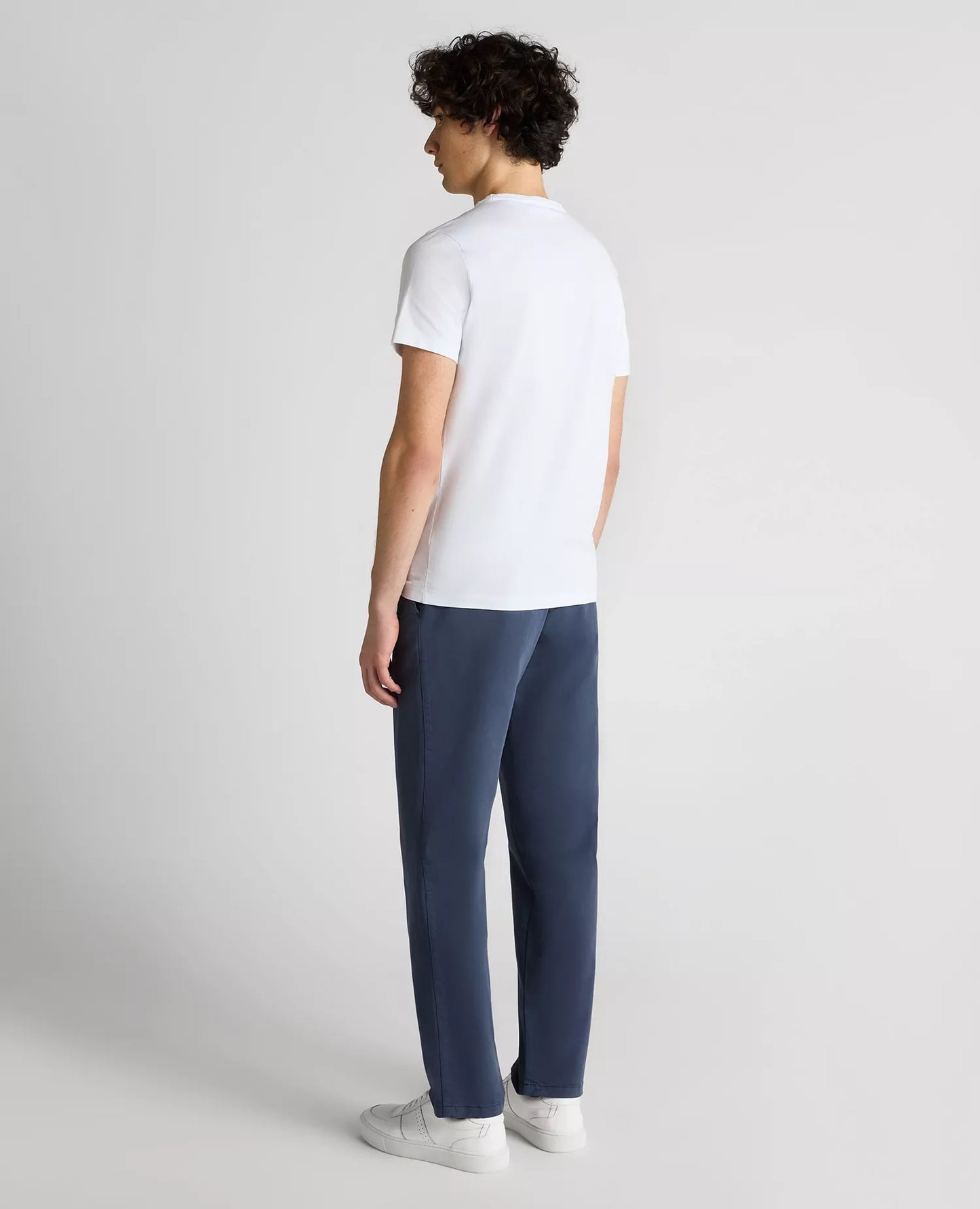 Person wearing a white t-shirt and navy pants on a light gray background