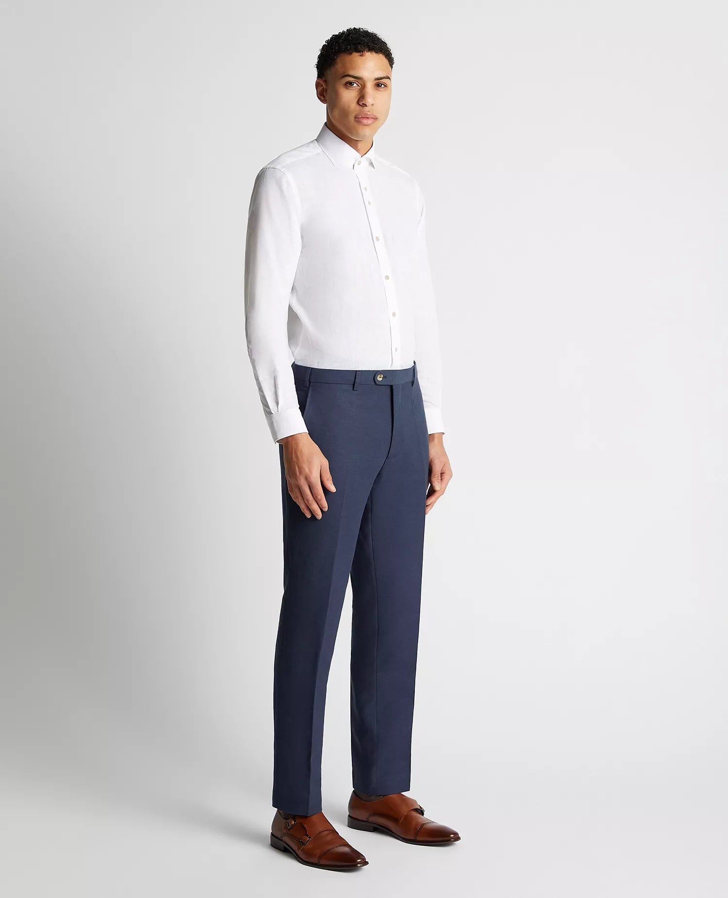 Man wearing a white dress shirt and blue dress pants on a light gray background