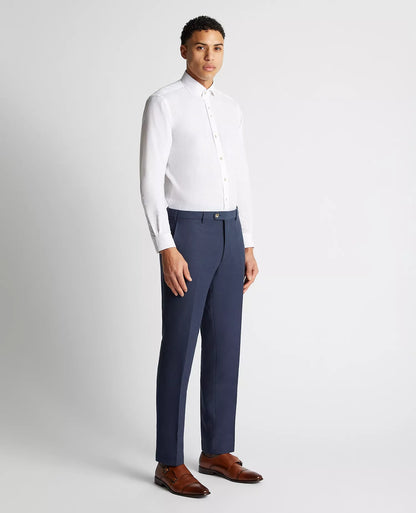 Man wearing a white dress shirt and blue dress pants on a light gray background