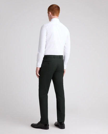 A man viewed from the back wearing a white long-sleeve dress shirt, dark charcoal gray trousers, and black dress shoes, standing against a light gray studio background.