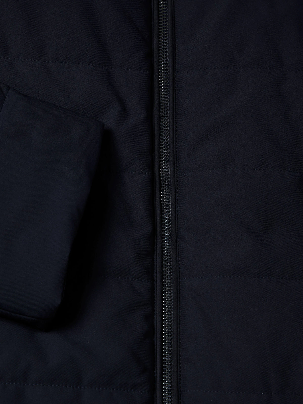 Close-up of a dark navy quilted jacket with a central zipper and a pocket on the left side.