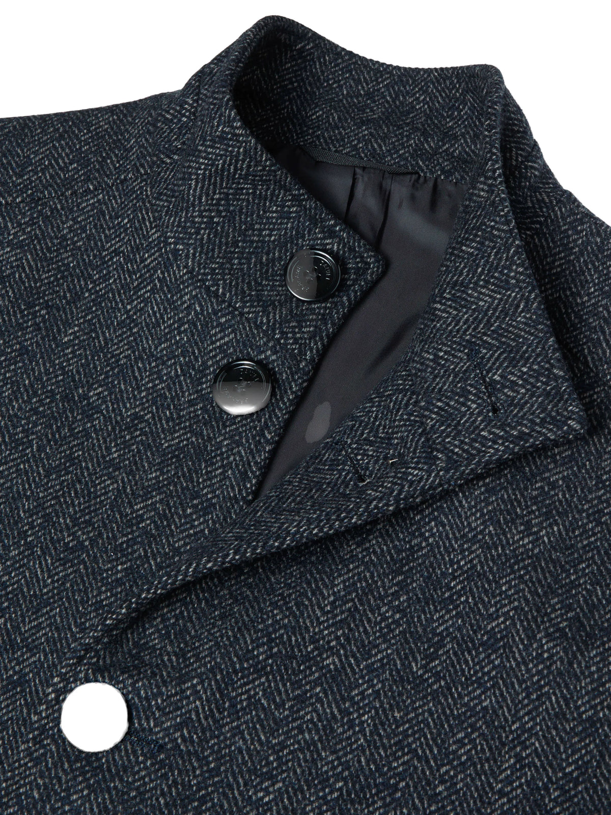 Close-up of a dark navy and gray herringbone patterned coat with a structured collar and dark buttons.