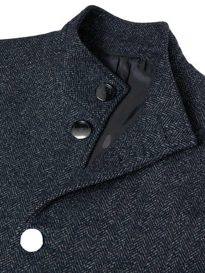 Close-up of a dark navy and gray herringbone patterned coat with a structured collar and dark buttons.