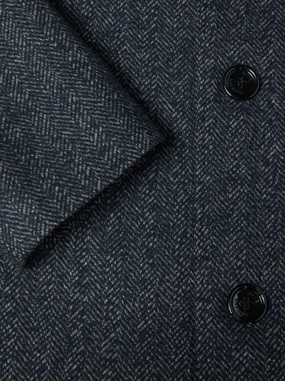Close-up of a dark navy blue herringbone tweed fabric with black buttons.