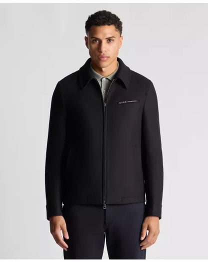 Man wearing a black jacket with a visible brand logo on a light gray background