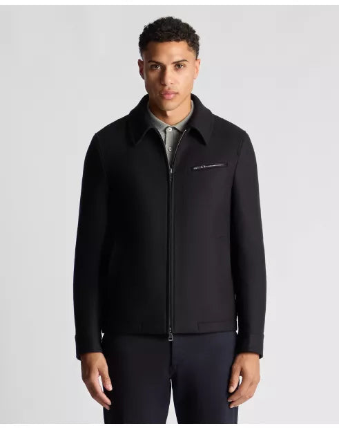 Man wearing a black jacket with a visible brand logo on a light gray background