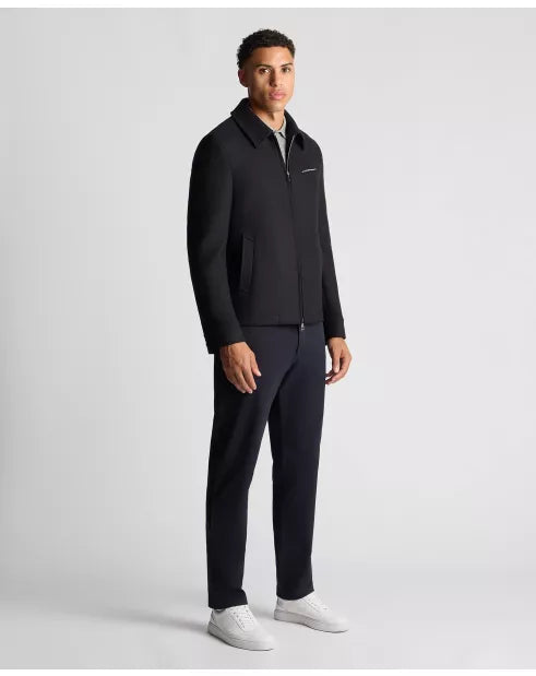 Man wearing a black jacket and pants on a light gray background