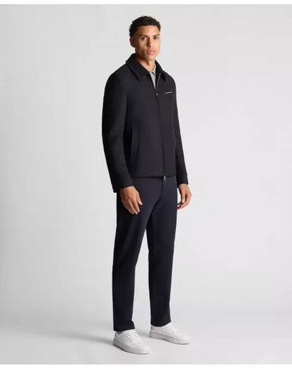 Man wearing a black jacket and pants on a light gray background