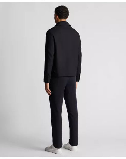 Person wearing a black suit on a light gray background