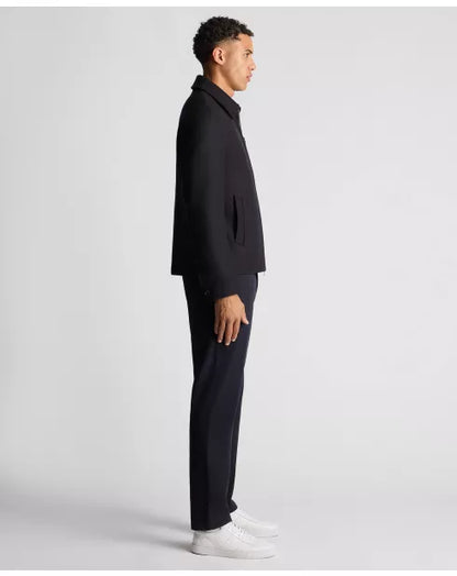 Man wearing a black suit and white shoes on a light gray background