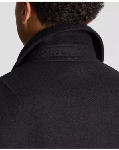 Person wearing a dark coat with a plain background