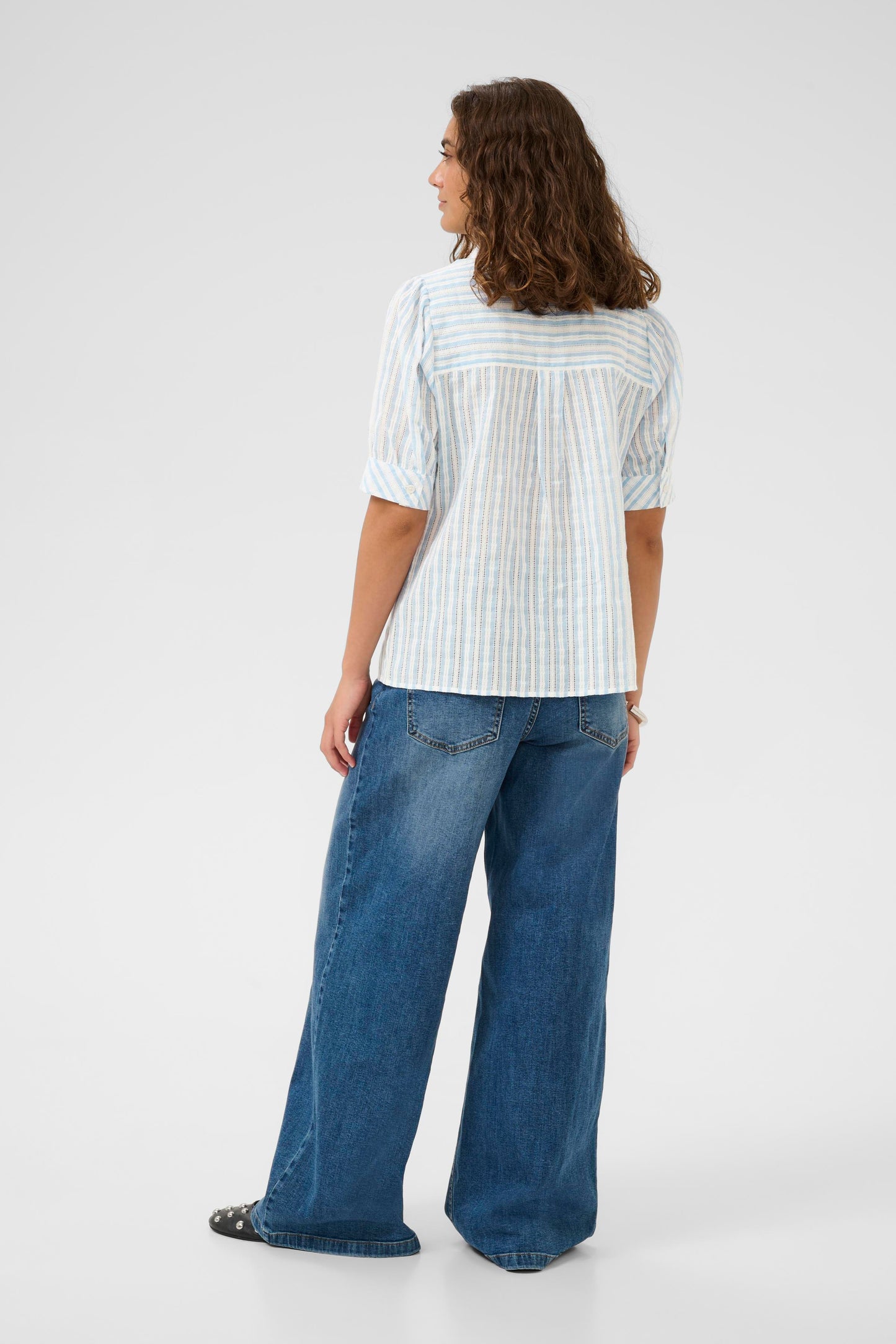 Person wearing a white striped shirt and blue jeans on a white background